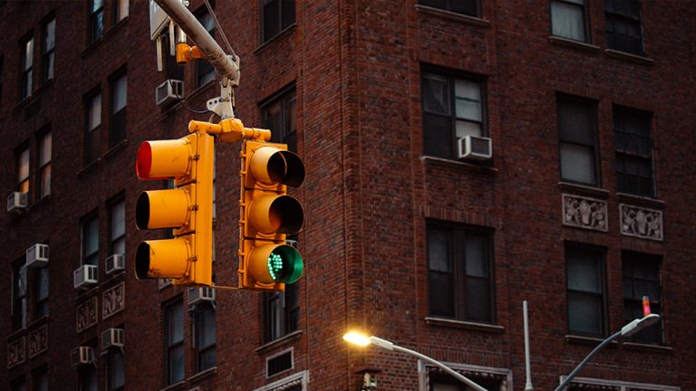 Street lights hanging over an intersection with red and green lit
